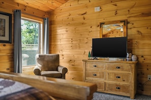 A wooden cabin interior with a bed, a chair, a dresser, and a television on top. - Sleeps 10, Game Room, Hot Tub, Two Fireplaces, 4 Mi to Downtown Gatlinburg (Gatlinburg)