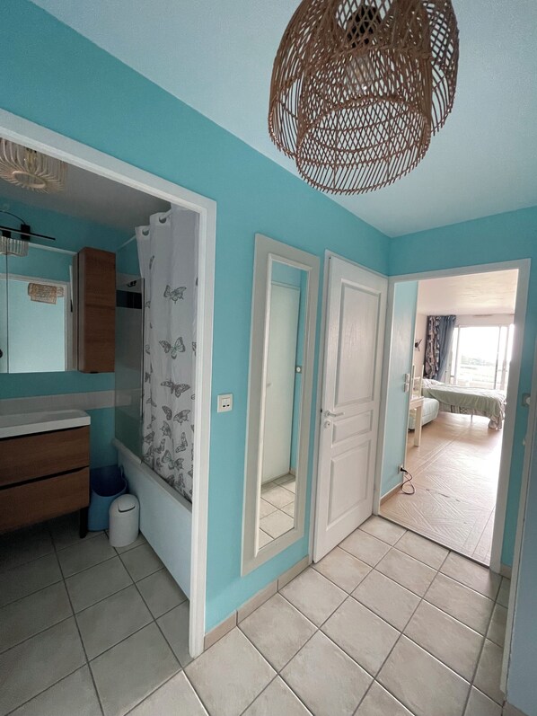 Una habitación con baño, una cama y una puerta que da a otra estancia.