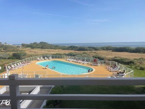 A pool area with a view of the sea, surrounded by lounge chairs and a fenced deck. - ☀️ Getaway with a sea view • Swimming Pools • Wild Coast (Les Sables-d'Olonne)
