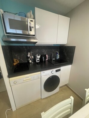 A compact kitchen with a microwave, coffee maker, and a washing machine. - ☀️ Getaway with a sea view • Swimming Pools • Wild Coast (Les Sables-d'Olonne)