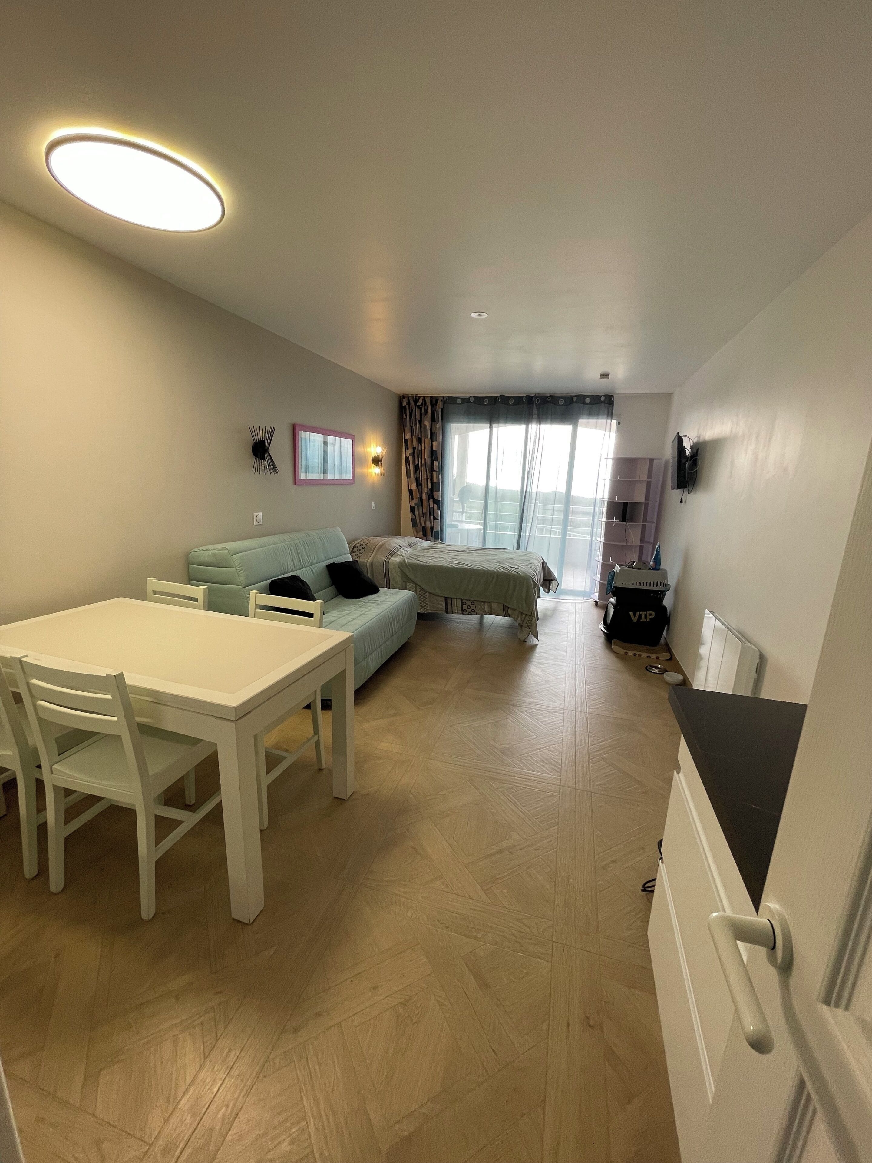 A modern living room with a dining table, sofa, and a TV mounted on the wall.