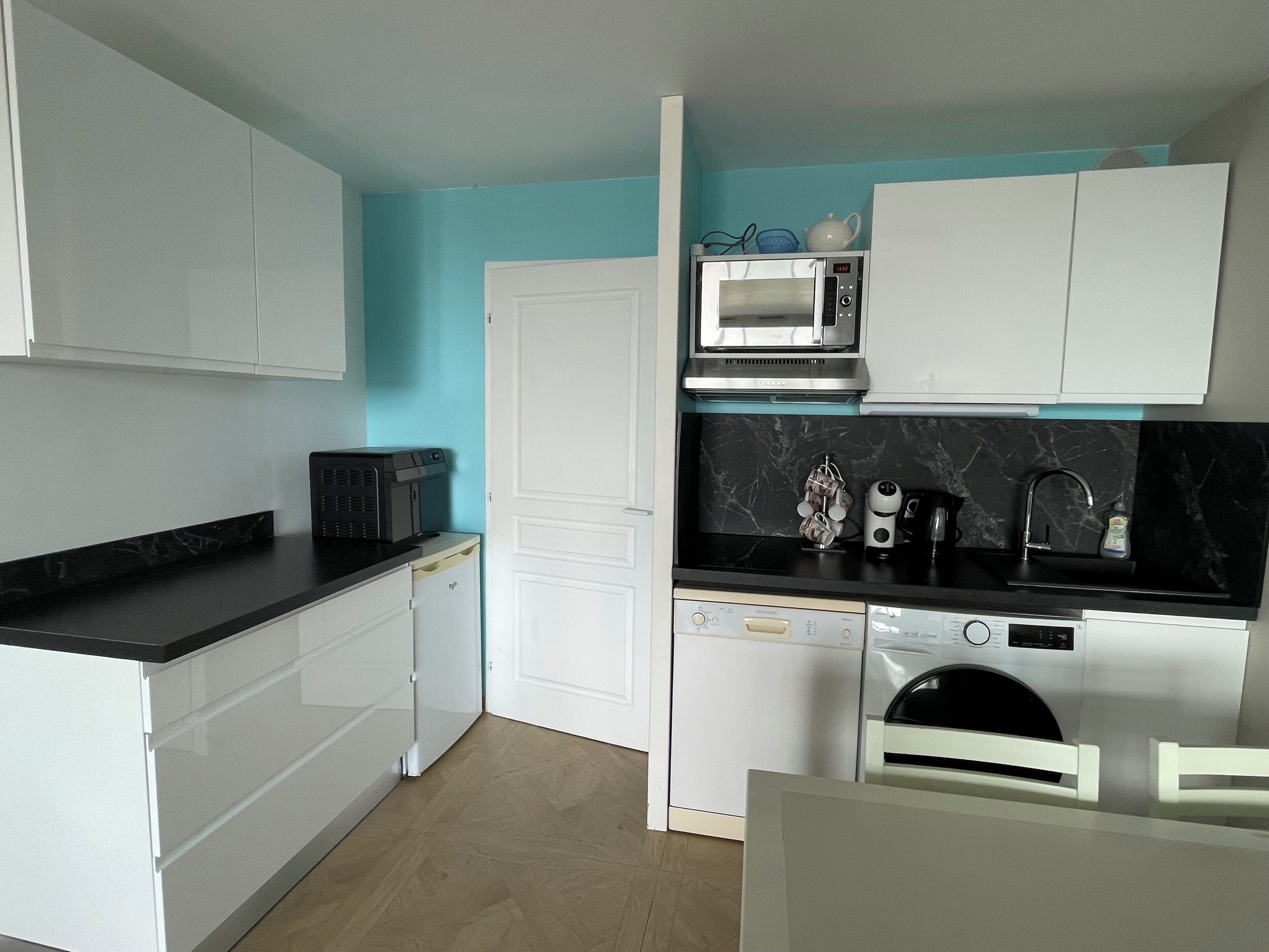 A compact kitchen with white cabinetry, a microwave, a coffee maker, and a dishwasher.