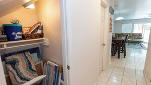 Um corredor leva a uma sala de jantar com mesa e cadeiras, um recipiente azul e um quadro na parede.