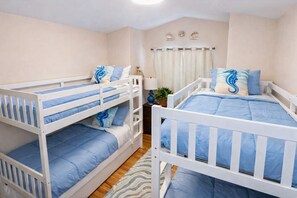 Ein Zimmer mit Etagenbetten, einem Nachttisch mit Lampe und einem fenster mit Vorhängen.