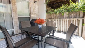 Eine Terrasse im Freien mit Tisch und Stühlen, einem Blumentopf und einem Holzzaun.