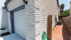 Eine Garage mit weißer Tür, Ziegelwand und Holztor.