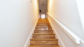 Eine Holztreppe mit weißen Wänden und einer Deckenleuchte.