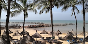 A beach with palm trees, thatched umbrellas, and lounge chairs. - Beautiful private villa in a gated community with a garden—centrally located, with everything within walking distance! (Saly)