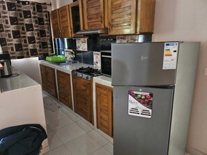 A kitchen with wooden cabinets, a Bosch refrigerator, a stove, and a sink. - Beautiful private villa in a gated community with a garden—centrally located, with everything within walking distance! (Saly)