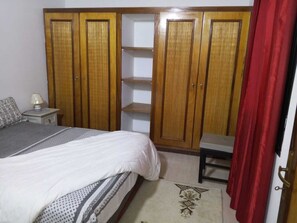 A bedroom with a bed, a nightstand, a wardrobe, and a chair. - Beautiful private villa in a gated community with a garden—centrally located, with everything within walking distance! (Saly)