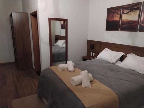 A hotel room with a bed, a wooden wardrobe, a mirror, and artwork on the wall. - POUSADA ALTO DOS PINHEIROS (Camanducaia)