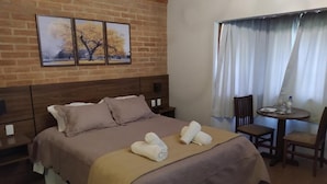 A hotel room with a large bed, a small table, and a chair.