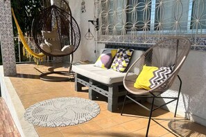 Um pátio ensolarado com rede, área de estar acolchoada e parede decorativa.