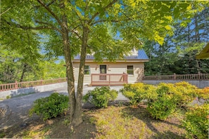 A house with a porch, surrounded by trees and shrubs. - Mountain Escape - Hot Tub - Game Room - Sleeps 8 (Pigeon Forge)
