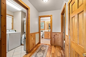 A hallway with wooden doors, a tiled floor, and a view into a bathroom with a toilet and sink. - Mountain Escape - Hot Tub - Game Room - Sleeps 8 (Pigeon Forge)