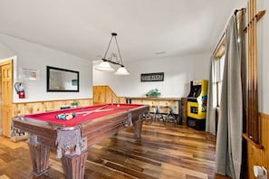 A pool table with a red felt surface, a wooden floor, and a Game Room sign on the wall. - Mountain Escape - Hot Tub - Game Room - Sleeps 8 (Pigeon Forge)