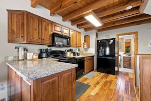 A kitchen with wooden cabinets, granite countertops, a black refrigerator, and a microwave. - Mountain Escape - Hot Tub - Game Room - Sleeps 8 (Pigeon Forge)