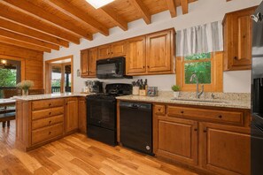 A kitchen with wooden cabinets, a microwave, stove, and dishwasher. - Mountain Escape - Hot Tub - Game Room - Sleeps 8 (Pigeon Forge)