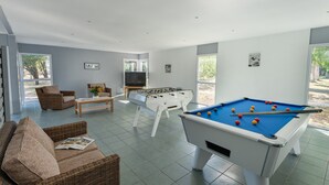 A spacious living area with a pool table, a foosball table, and comfortable seating.