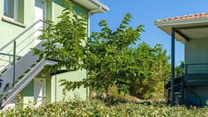 A two-story building with a green exterior, a visible staircase, and a tree in front.
