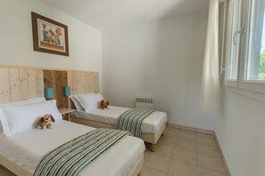 A hotel room with two beds, a wooden headboard, a framed picture on the wall, and a window with curtains.