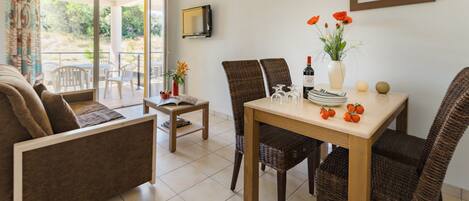 A dining area with wicker chairs, a wooden table, and a view through a glass door to an outdoor patio.