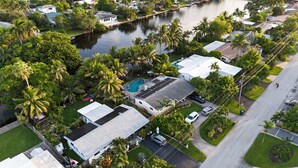 Ett flygbildsbild av ett bostadsområde med hus, en swimmingpool och en brygga vid ett vattendrag.