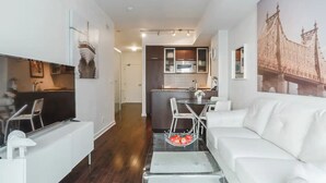 A modern living room with a white sofa, a dining area with a glass table, and a kitchen in the background. - Harbour Skyline (Toronto)