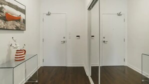 A hallway with two white doors, a glass cabinet with a striped vase, and a framed picture on the wall. - Harbour Skyline (Toronto)