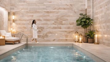 Ein Spa-Bereich mit Pool, Marmorwand, Liegestuhl, Topfpflanze und Wandleuchten.