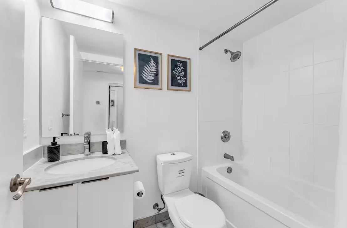 Une salle de bain moderne avec un lavabo, des toilettes et une baignoire. Des tableaux encadrés ornent le mur.