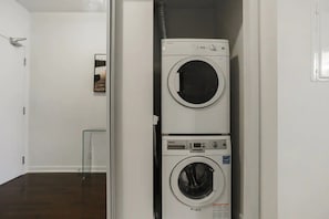 Un cuarto de lavandería con dos lavadoras apiladas y una secadora.