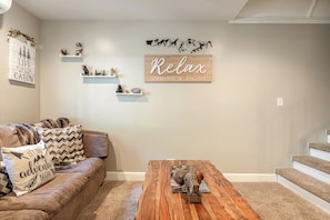 A living room with a sofa, coffee table, and decorative items on shelves. - Adventure in the Trees (Lake Arrowhead)