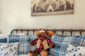 A bed with a headboard, a plush toy, and patterned pillows. - Adventure in the Trees (Lake Arrowhead)