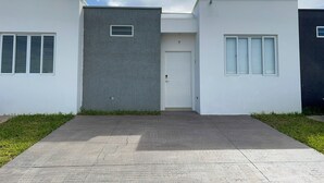 Un edificio moderno con techo plano, una puerta central y dos ventanas laterales.