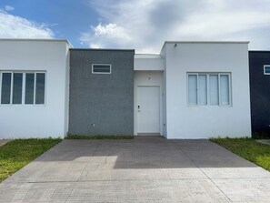 Ein modernes Gebäude mit flachem Dach, einer Zwerchhaustür und zwei Seitenfenstern.