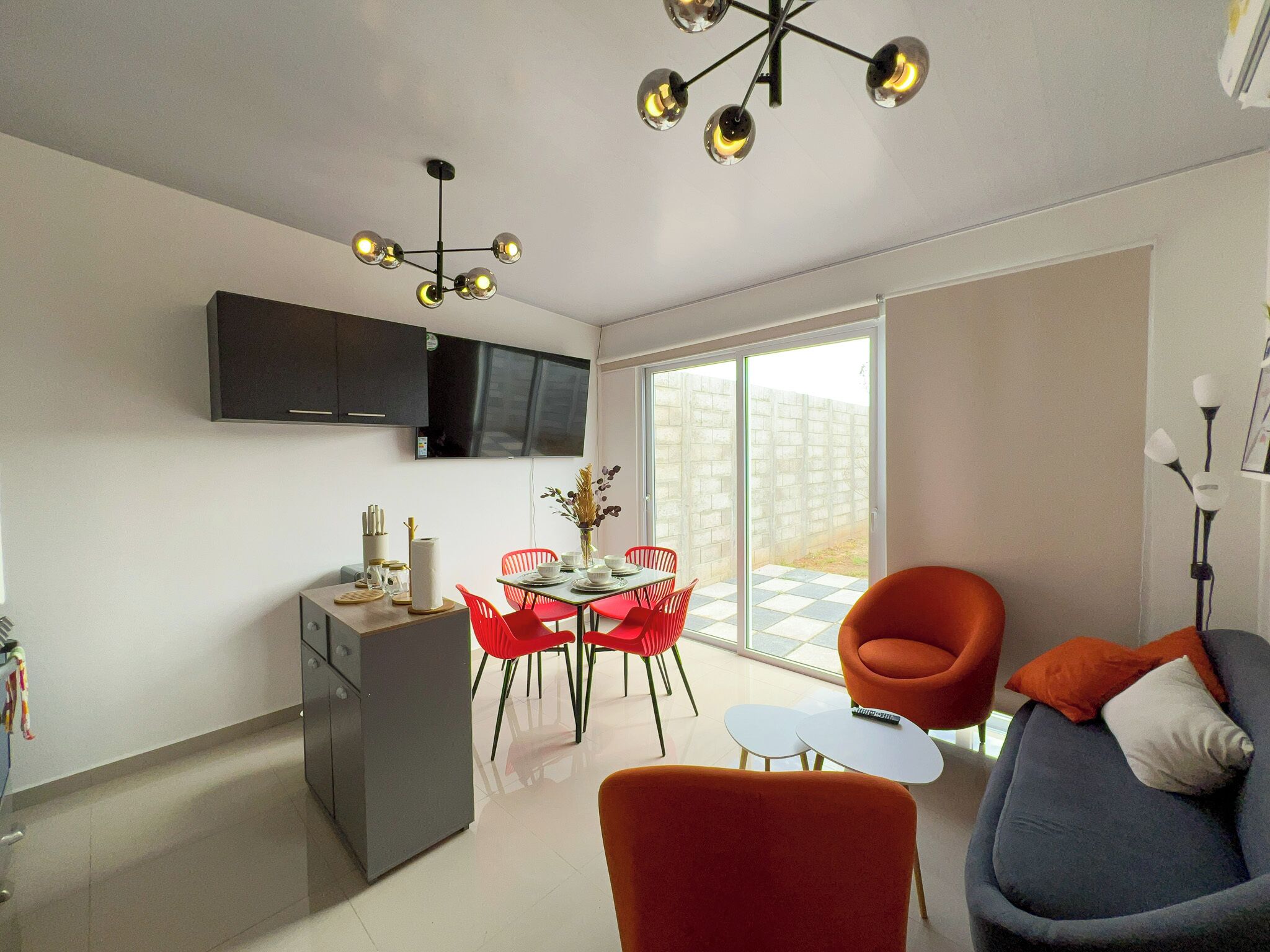 A modern living space with a dining area, a sofa, and a TV mounted on the wall.