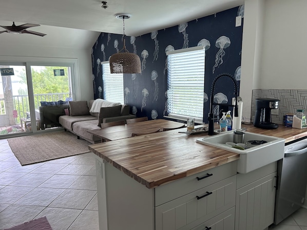 A modern kitchen with a wooden countertop, white cabinets, and a built-in sink.