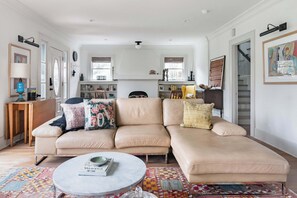 A living room with a beige sofa, a round coffee table, and a patterned rug. - Historic Houston Midtown Haven (Houston)