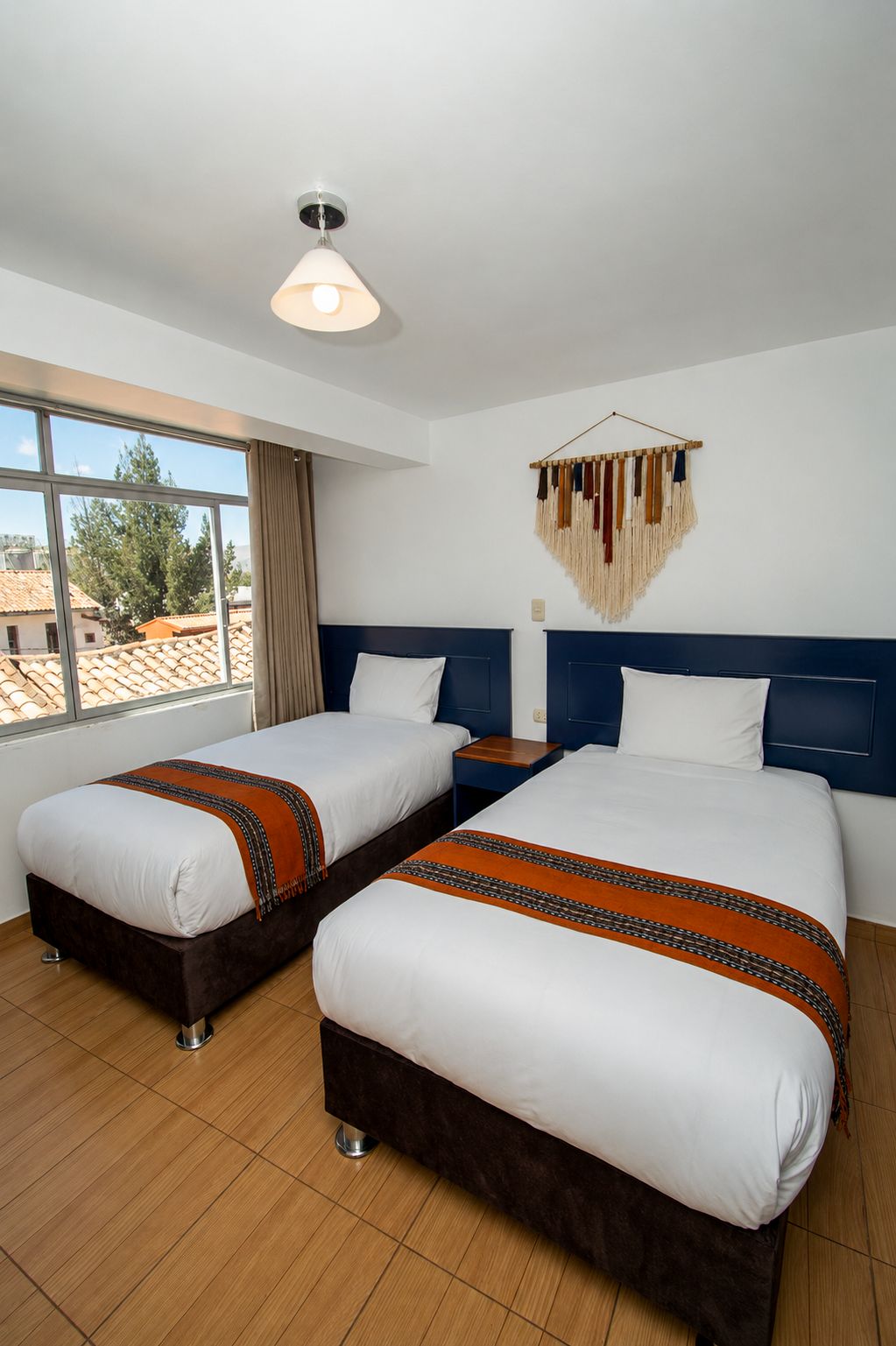 Una habitación de hotel con dos camas, un ventanal grande y un adorno en la pared.