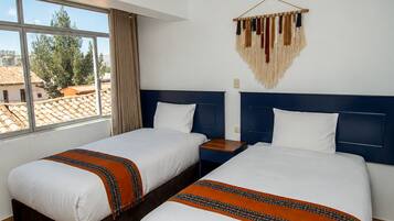 Una habitación de hotel con dos camas, un ventanal grande y un adorno en la pared.