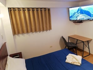 A hotel room with a bed, a desk, a chair, a television, and a curtain. - Inkarri Express Cusco (Cusco)