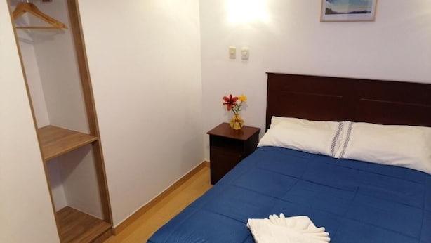 Un dormitorio con cama, una mesita de noche, un tocador con un florero y un armario de madera.