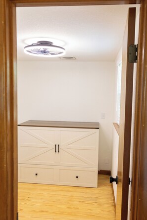 A room with a wooden floor, a white cabinet with drawers, and a ceiling light fixture. - Hill County Tiny Home on 5 Acres - near wedding venues (Austin)