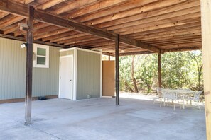 An open covered patio with a concrete floor, a door, and a table with chairs. - Hill County Tiny Home on 5 Acres - near wedding venues (Austin)