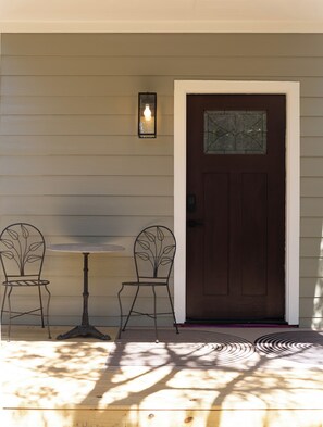 A wooden door with a glass panel, two metal chairs with leaf designs, and a small table. - Hill County Tiny Home on 5 Acres - near wedding venues (Austin)