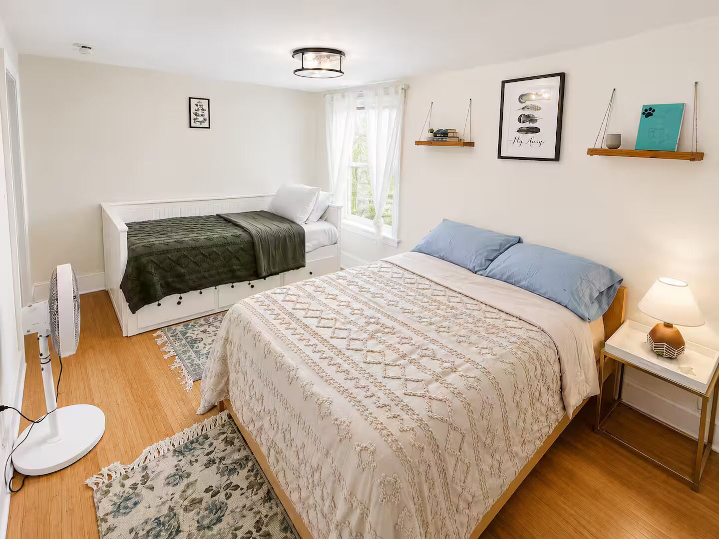 A bedroom with a bed, bedside table, lamp, and a window with curtains.
