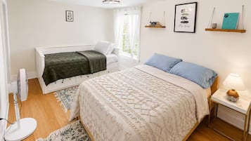 A bedroom with a bed, bedside table, lamp, and a window with curtains.