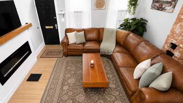 A living room with a brown leather sofa, a wooden coffee table, and a patterned rug.