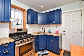 A kitchen with blue cabinets, a stainless steel stove, and a white door. - Cozy & Modern Home in University City, Philadelphia (Philadelphia)